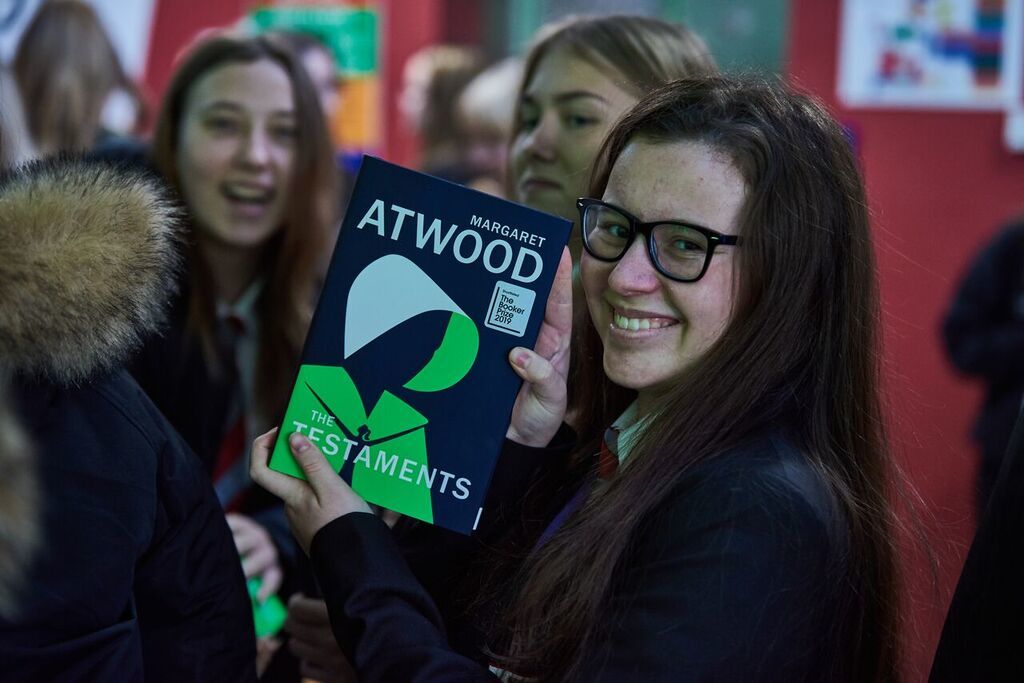 Students grinning with their copies of The Testaments.